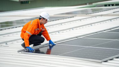 Evin çatısına fotovoltaik güneş modülleri monte eden bir inşaatçı. Güneş paneli sistemi kuran miğferdeki insan mühendisin arka görüntüsü. Alternatif ve yenilenebilir enerji kavramı.