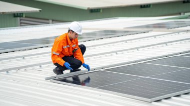 Evin çatısına fotovoltaik güneş modülleri monte eden bir inşaatçı. Güneş paneli sistemi kuran miğferdeki insan mühendisin arka görüntüsü. Alternatif ve yenilenebilir enerji kavramı.