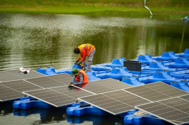 Fotovoltaik mühendisleri yüzen fotovoltaikler üzerinde çalışıyorlar. Güneş paneli ekipmanlarını incele ve onar
