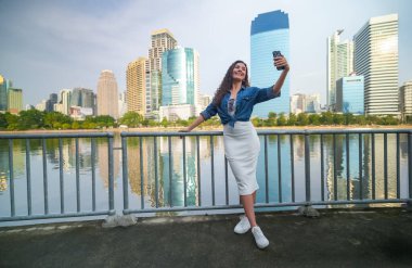 Mutlu Asyalı kadın cep telefonuyla selfie çekiyor.