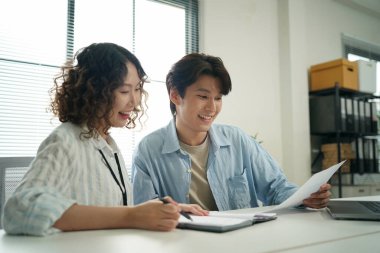 Genç Asyalı erkek ve kız öğrenci dizüstü bilgisayarla birlikte çalışıyor.