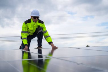 Erkek teknisyenler fotovoltaik güneş modüllerini evin çatısına monte ediyorlar..