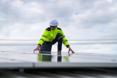 Erkek teknisyenler fotovoltaik güneş modüllerini evin çatısına monte ediyorlar..