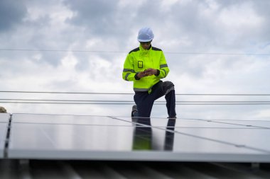 Erkek teknisyenler fotovoltaik güneş modüllerini evin çatısına monte ediyorlar..