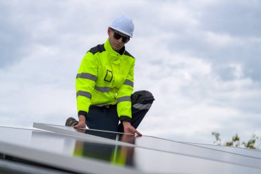 Erkek teknisyenler fotovoltaik güneş modüllerini evin çatısına monte ediyorlar..