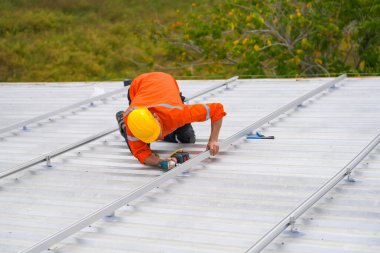 Erkek teknisyenler fotovoltaik güneş modüllerini evin çatısına monte ediyorlar..