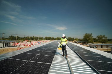 Fotovoltaik güneş modülleri monte eden erkek teknisyenler. Evin çatısına fotovoltaik güneş modülleri monte eden bir inşaatçı. Güneş paneli sistemi kuran miğferdeki insan mühendisin arka görüntüsü. Alternatif ve yenilenebilir enerji kavramı.