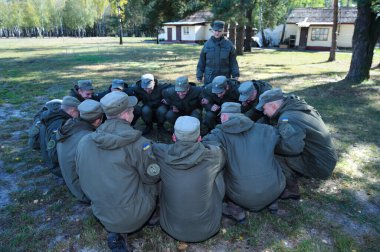 Takım oluşturma egzersizi: askerler yerde oturuyor ve birbirlerinin ellerini tutuyorlar. 18 Ekim 2018. Novo-Petrivtsi askeri üssü, Ukrayna