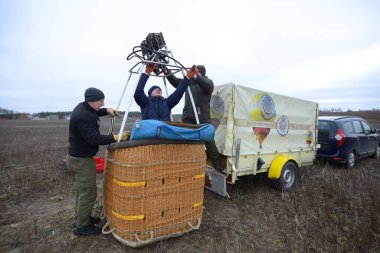 Balon şişirme hazırlıkları: erkek işçiler gaz ocağını arka planda ekipman bulunan sepetin, arabanın ve römorkun üstüne koydular. 12 Ocak 2020. Kyiv, Ukrayna