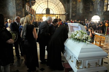Burial service in a church. Relatives in black mourning clothes giving the last farewell to late lying in white coffin. August 10, 2017. Kyiv, Ukraine