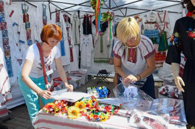 Women sellers put clothes on counter waiting for customers before opening at Ukrainian national embroidery shirts street stall. August 25, 2019. Kyiv, Ukraine