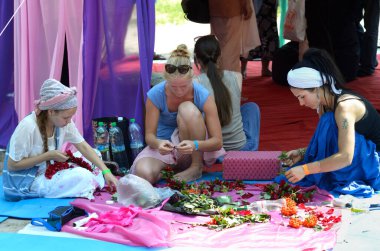 Doğulu gibi giyinmiş kadınlar yere oturup çiçek süslemesi yapıyorlar. Vedalife Festivali. 7 Ağustos 2017. Kyiv, Ukrayna