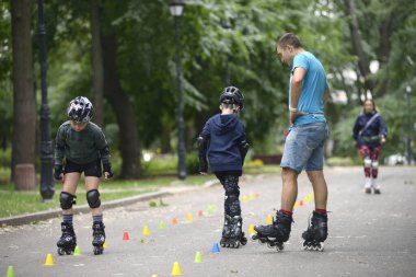 Paten kaymak. Antrenör, çocuk hareketlerini düzeltiyor. Sanatsal slalom öğretiyor. 25 Haziran 2019. Kiev, Ukrayna
