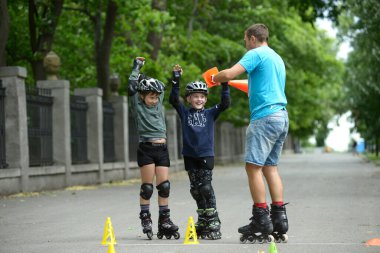 Paten kaymak. Şehir parkında çocuklara sanatsal slalom öğreten eğitmen. 25 Haziran 2019. Kyiv Ukrayna