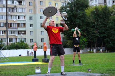 Adam bir stadyuma ağırlık atıp hokkabazlık yapıyor. Fiziksel kültür ve spor üniversitesinin açılışı. 20 Haziran 2019. Kyiv, Ukrayna