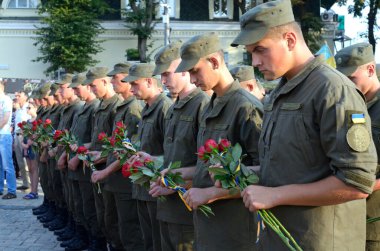 Askeri üniformalı Ukraynalı askerler bir sıra halinde ve ellerinde kırmızı çiçek buketleri tutuyorlar. Ilovaisk Savaşı 'nın yıldönümüne adanmış bir toplantı. 28 Ağustos 2018. Kyiv, Ukrayna