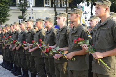 Askeri üniformalı Ukraynalı askerler bir sıra halinde ve ellerinde kırmızı çiçek buketleri tutuyorlar. Ilovaisk Savaşı 'nın yıldönümüne adanmış bir toplantı. 28 Ağustos 2018. Kyiv, Ukrayna