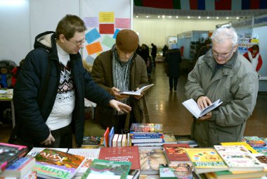Kitapçı, kitapçı tezgahında iki yaşlı adama kitap satıyor. Kitap fuarı. 24 Mayıs 2019. Kyiv, Ukrayna