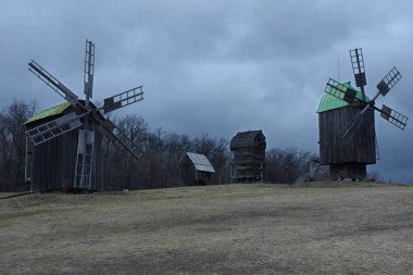 Akşam ışığında çalışan eski ahşap yel değirmenleri. Pyrogove Köyü, Ukrayna.