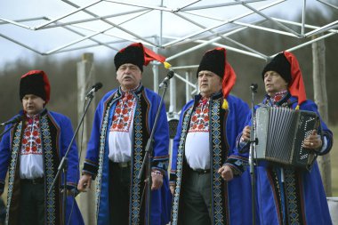 Ukrayna 'da geleneksel Kazak kostümleri giyen erkekler sahnede şarkı söyleyip Masnytsya' yı kutluyorlar - putperest kışa veda bayramı. 10 Mart 2019. Pyrogove, Ukrayna