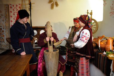 Ukrayna yerlisi kostümlü aile, Noel arifesini kutlamak için geleneksel tabak kutia pişirmek üzere toplandı. Ukrayna gelenekleri, yeniden yapılanma. 4 Ocak 2018. Kyiv, Ukrayna