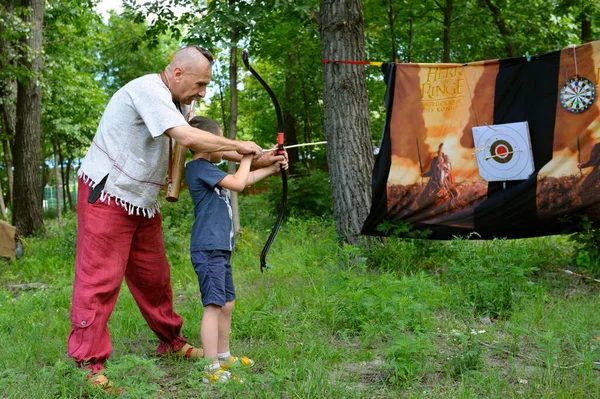 男子弓箭手穿得像古代的奴隶战士 教小男孩射箭 2018年8月2日 乌克兰基辅Murometz公园 — 图库照片