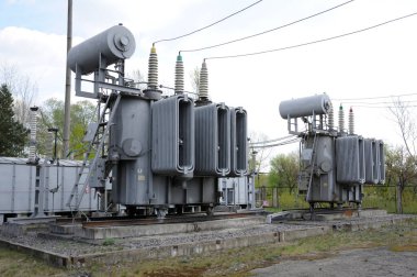 Transformer, insulators and part of high-voltage lines of an electric substation clipart