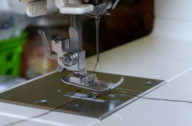 Dikiş makinesi çalışıyor iğne çubuğu, baskılı ayak, iğne tabağı, iplikle beslenen köpek ve iğne..