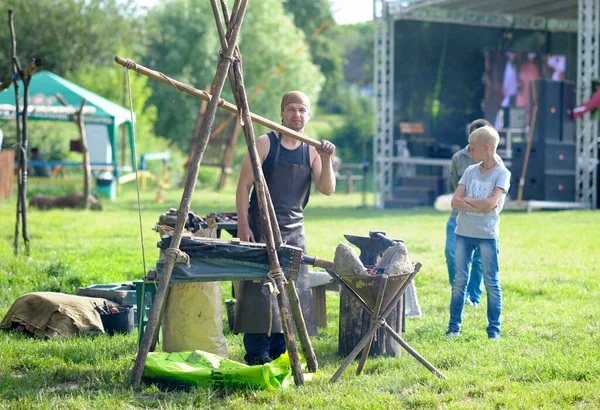 Młody Kowal Pracujący Tradycyjnej Kuźni Plenerowej Łotewskiego Rocznika Oglądający Dzieci — Zdjęcie stockowe