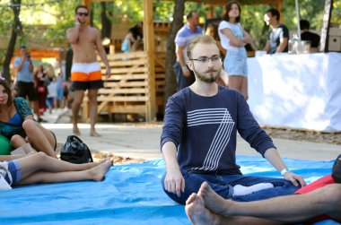 İnsanlar bir yerde oturur ve şehir parkında vaaz veren guruları dinlerler. Vedalife Festivali. 25 Temmuz 2018. Kyiv, Ukrayna