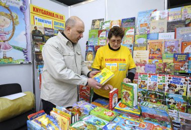 Kadın kitapçı fiyatını soran bir kitabı elinde tutan adam. Kitap fuarı. 14 Aralık 2017. Kyiv, Ukrayna