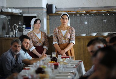 Tatar restoranında: Tatar yerlisi elbiseli garsonlar masada yemek yerken tezgahın yanında duruyorlar. 8 Eylül 2018. Kyiv, Ukrayna