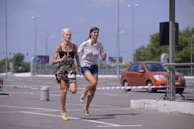 Sıradan elbiseli ve yüksek topuklu ayakkabılı kızlar bahis için sokakta koşuşturuyor. 3 Temmuz 2013. Kyiv, Ukrayna
