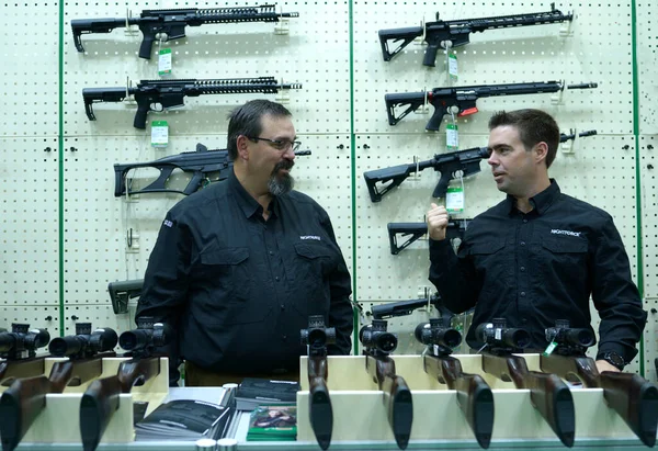 Silah dükkanının tezgahında konuşan iki satıcı, tüfekleri tezgaha yerleştirip arka planda duruyorlar. 08 Ekim 2019. Kiev, Ukrayna
