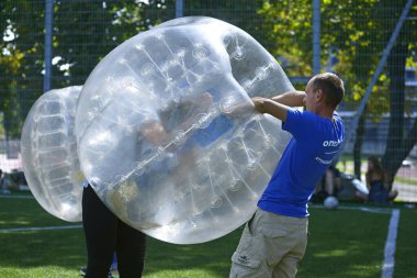 Balonlu futbol. Adam oyuncunun balonun içine girmesine yardım ediyor. 12 Ağustos 2019. Kiev Ukrayna