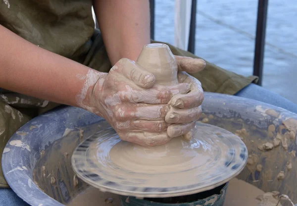 Teaching of wheel throwing. Potter hand correcting woman s ones during shaping clay blank on a potter\'s wheel.