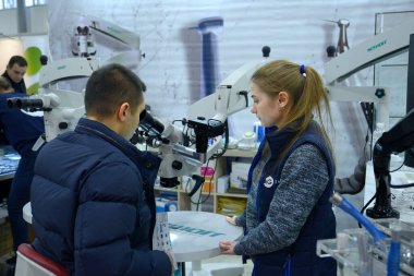 Dükkanda. Bayan yönetici müşteriye diş cerrahisi mikroskobundan bahsediyor. 27 Kasım 2019. Kiev, Ukrayna