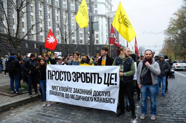 Sokakta yürüyen insanlar, ellerinde yayınlarla tıbbi marihuananın yasallaştırılmasını talep eden, arka planda Ukrayna Bakanlar Kurulu binası kuran insanlar. 26 Ekim 2019. Kyiv, Ukrayna