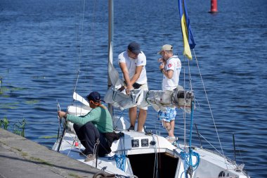 Erkek yatçılar yarıştan önce yelkenli bir yat hazırlıyor. 24 Ağustos 2019. Kiev, Ukrayna