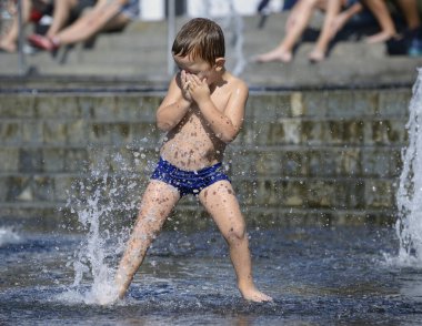 Küçük çocuk meydanda fıskiye jetleri ile oynuyor. 5 Haziran 2019. Kiev, Ukrayna