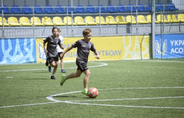 Futbol tişörtlü ve botlu çocuklar stadyumda futbol oynuyorlar. 11 Ekim 2021. Kyiv, Ukrayna