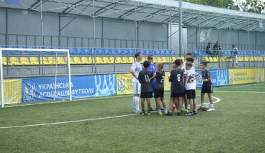 Maç sonrası futbol tişörtlü ve çizmeli çocuklarla stadyumda maç analizi yapan bir adam koçu. 11 Ekim 2021. Kyiv, Ukrayna