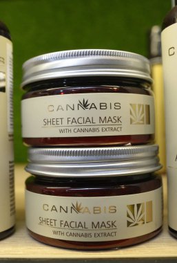 Esrar özlü kozmetik ürünleri. Bir dükkânın tezgahına, maske takılmış cam kutular. Esrar fuarı. 2 Ekim 2020. Kyiv, Ukrayna