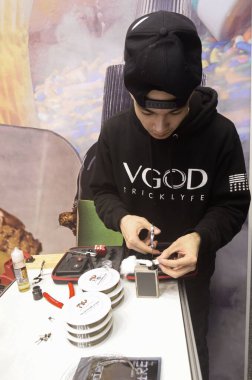 Masadaki tüpü tamir eden genç bir çocuk. Akko Uluslararası Fuar Merkezi 'nde Vape Ticaret Fuarı. 19 Mart 2017. Kiev, Ukrayna