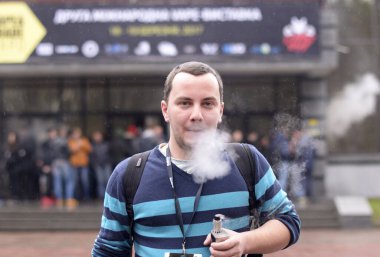 Genç şehirli adam bulanık kalabalığın önünde sigara içiyor. 20 Mart 2017. Kiev, Ukrayna