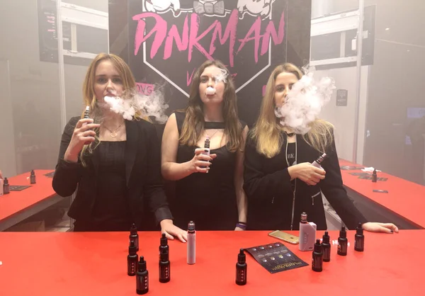 Três Jovens Moças Hipster Urbanas Fumando Vapores Stand Promovendo Cigarros Fotos De Bancos De Imagens