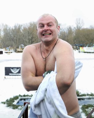 Orta yaşlı, kalın elbiseli kadınlar vaftiz töreninden sonra röportaj veriyorlar. Büyük baş parmaklar iyi hissettiklerini gösteriyor. Dnipro Nehri 'nde Epifani bayramı. 19 Ocak 2019. Kyiv, Ukrayna