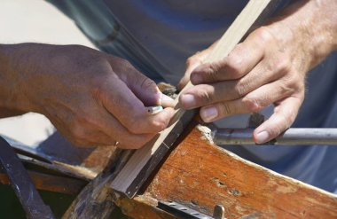 Ahşap işçilerinin elleri bir teknenin ahşap kısmını işaret eden bir kalem tutuyorlar.