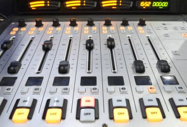 Düğmeler, ses seviyeleri, ses karıştırıcı kontrol paneli radyo stüdyosundaki bir masada çalışıyor.