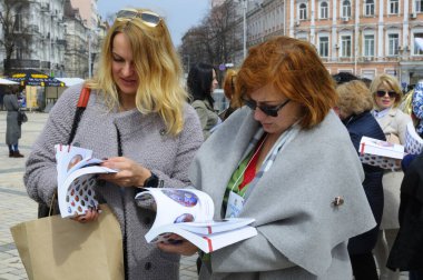 Aynı anda broşür okuyan bir grup genç kadın. Halk sanatı festivali. 18 Nisan 2018. Kyiv, Ukrayna